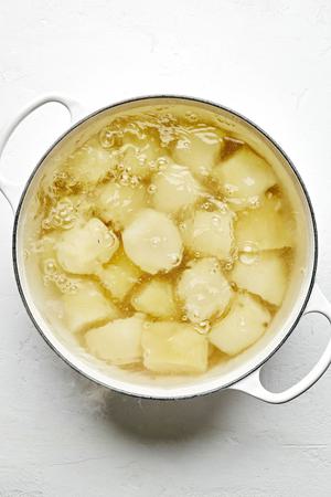 russet potatoes being boiled in a pot of water to make classic mashed potatoes