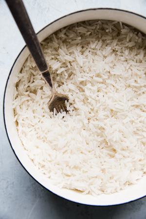 homemade coconut rice in a pot being stirred with a spoon