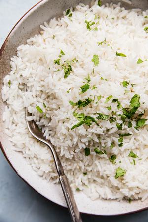 A bowl of creamy coconut rice made with coconut milk, salt, and sugar, garnished with a touch of cilantro