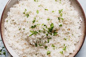 A bowl of creamy coconut rice made with coconut milk, salt, and sugar, garnished with a touch of cilantro