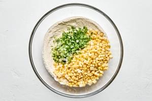 corn, green onions, flour, cornmeal, sugar, baking powder, salt, cayenne, and garlic powder in a bowl