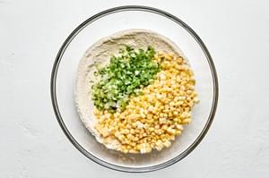 corn, green onions, flour, cornmeal, sugar, baking powder, salt, cayenne, and garlic powder in a bowl
