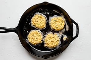 homemade corn fritters being fried in butter and oil in a skillet
