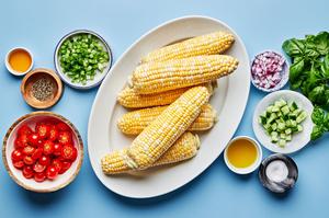 corn, cherry tomatoes, cucumber, red onion, green onions, basil, lime juice, olive oil, honey, salt and pepper in prep bowls