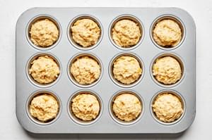 A 12-muffin pan filled with uncooked cornbread muffin mix