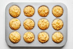 A 12-muffin pan filled with perfectly-baked cornbread muffins