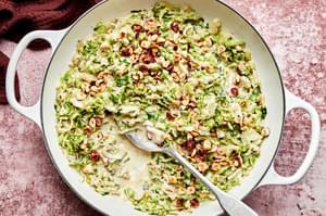 creamed brussels sprouts made with heavy cream and parmesan topped with toasted hazelnuts in a skillet