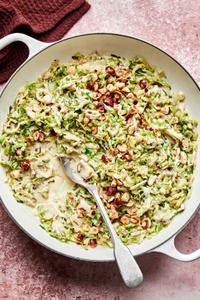 creamed brussels sprouts made with heavy cream and parmesan topped with toasted hazelnuts in a skillet