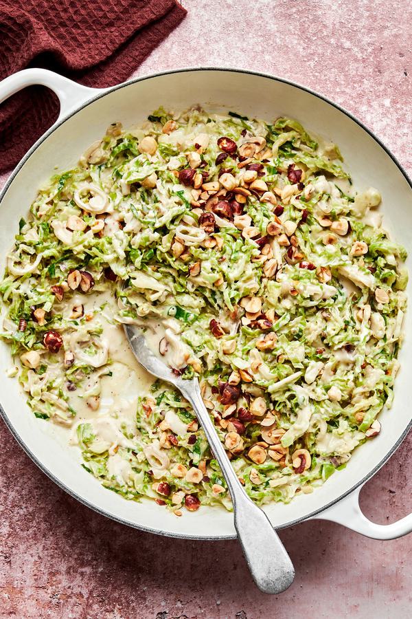 creamed brussels sprouts made with heavy cream and parmesan topped with toasted hazelnuts in a skillet