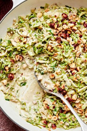 creamed brussels sprouts made with heavy cream and parmesan topped with toasted hazelnuts in a skillet
