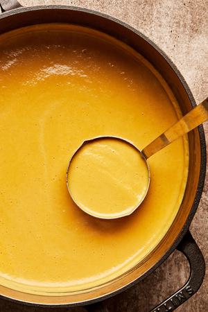 homemade cream of cauliflower soup in a pot being scooped with a ladle