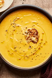 homemade cream of cauliflower soup drizzled with garlic oil and sprinkled with pepper in a bowl