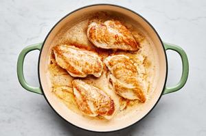chicken breasts seasoned with salt being browned in olive oil in a skillet