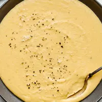 a bowl of homemade polenta made with milk, chicken stock, butter, salt, pepper and Parmesan topped with cracked pepper
