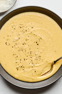 a bowl of homemade polenta made with milk, chicken stock, butter, salt, pepper and Parmesan topped with cracked pepper