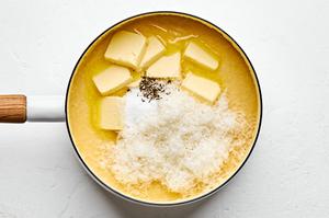 butter, Parmesan, salt and pepper being added to a sauce pan with chicken stock, milk and polenta