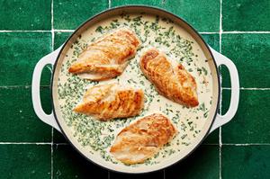 Four browned boneless skinless chicken breasts simmering in a cream sauce with tarragon and shallots