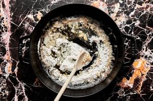 butter and flour being cooked in a skillet to make cream sauce