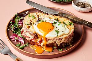 a homemade croque madame sandwich made with Béchamel sauce, ham, Gruyère & a fried egg topped with pepper, and chives
