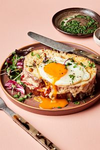 a homemade croque madame sandwich with Béchamel sauce, ham, Gruyère & a fried egg topped with pepper, and chives