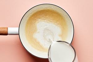 milk being poured into a pan with butter and flour