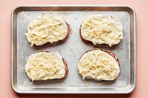 baked sandwiches with ham and Gruyère topped with béchamel sauce and more Gruyère on a baking sheet