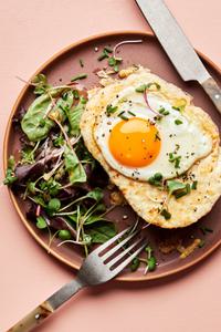 a homemade croque madame sandwich with Béchamel sauce, ham, Gruyère & a fried egg topped with pepper, and chives
