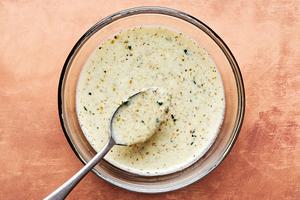 salad dressing made with Greek yogurt, yogurt, juice, olive oil, fresh mint, garlic, salt, pepper & za'atar in a glass bowl
