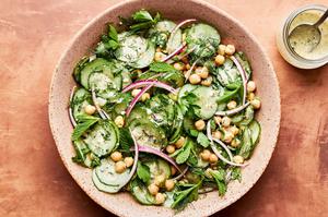 cucumber salad made with chickpeas, red onion, parsley, mint and dill with homemade salad dressing in a serving bowl