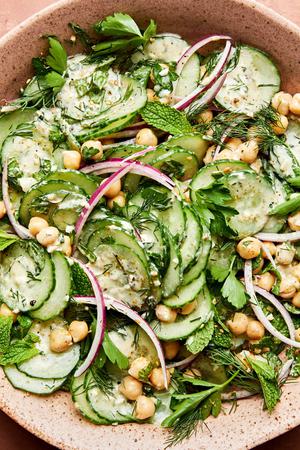 cucumber salad made with chickpeas, red onion, parsley, mint and dill with homemade salad dressing in a serving bowl