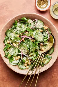 cucumber salad made with chickpeas, red onion, parsley, mint and dill with homemade salad dressing in a serving bowl