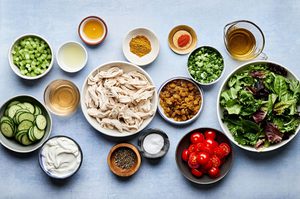 chicken, lettuce, tomatoes, cucumbers and other ingredients in bowls to make curried chicken salad salad