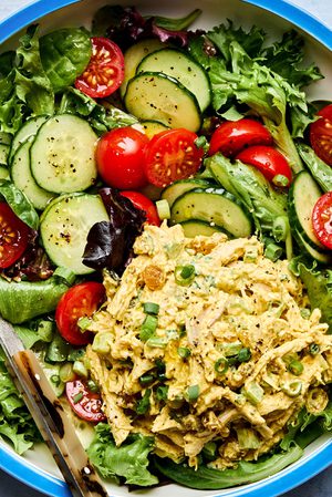 salad greens topped with cucumbers, tomatoes and curried chicken salad drizzled with homemade dressing