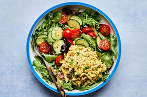 salad greens topped with cucumbers, tomatoes and curried chicken salad drizzled with homemade dressing