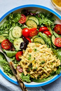 salad greens topped with cucumbers, tomatoes and curried chicken salad drizzled with homemade dressing