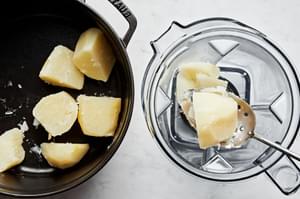 boiled potatoes being scooped into a blender