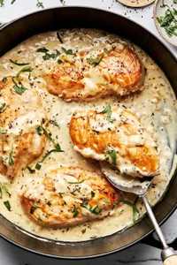 dijon chicken in a skillet made with cream, wine, dijon and sprinkled with pepper and fresh tarragon