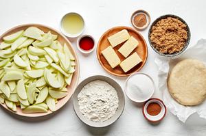 sliced apples, butter, flour, brown sugar, sugar, lemon juice, cinnamon, nutmeg and vanilla in bowls to make Dutch apple pie