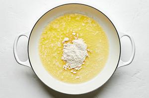 flour being added to a skillet with melted butter