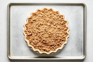 a dutch apple pie in a pie plate on top of a baking sheet ready to go in the oven