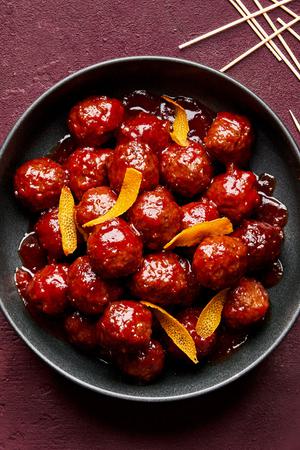 fig jam meatballs in a serving bowl made with fig jam, chili sauce and orange juice topped with orange zest