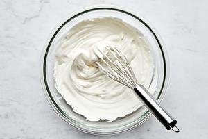 heavy cream being whipped with a whisk in a bowl to use for creamy tiramisu filling