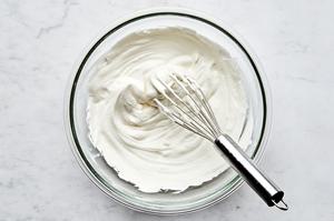 heavy cream being whipped with a whisk in a bowl to use for creamy tiramisu filling