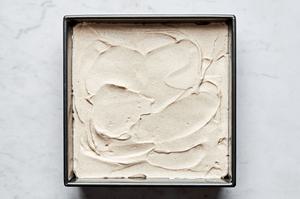 tiramisu being layered in a pan with layers of coffee soaked lady fingers and whipped spiced mascarpone