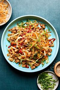 egg roll in a bowl drizzled with sriracha and sprinkled with wonton strips, green onions and sesame seeds