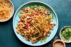 egg roll in a bowl drizzled with sriracha and sprinkled with wonton strips, green onions and sesame seeds