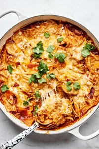 Skillet chicken enchiladas topped with melted cheese and fresh cilantro, a quick weeknight dinner
