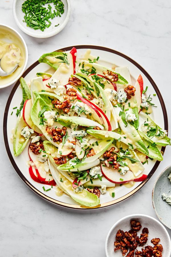 An Endive and Roquefort Salad sprinkled with candied walnuts and fresh chives on a serving plate