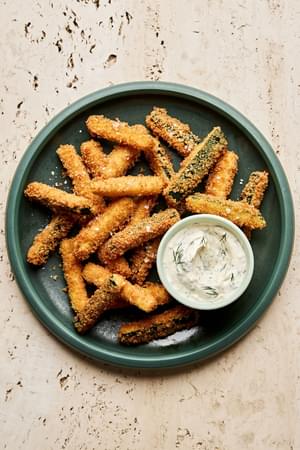 Golden-brown, extra crispy fried zucchini sticks sprinkled with flaky salt served with a side of creamy dill dip.