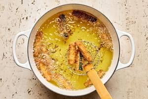 battered zucchini spears being deep fried in vegetable oil